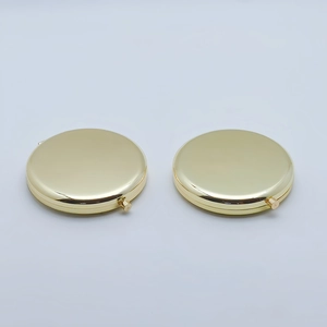 Pair of polished gold round metal folding makeup mirrors on a clean white background