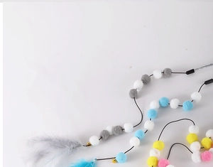 Detailed view of colorful cat wand toys with plush balls, feathers, and small bells on white
