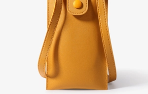 Close-up of ginger yellow leather mini phone bag with flap and snap button detail