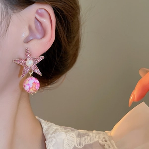 Close-up of starfish earrings with pink rhinestones and pearls on female model