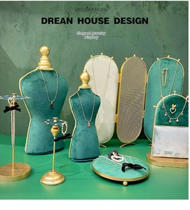 Macro detail of dark green velvet and matte gold metal jewelry display stand set