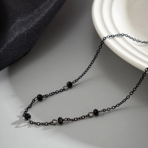 Detail of gothic black beaded choker necklace featuring faceted beads on a dark metal chain