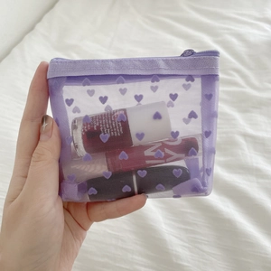 Detailed view of lavender heart mesh makeup bag with zipper and cosmetic items