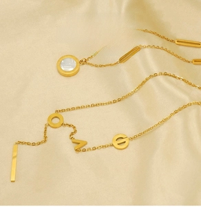 Close-up of gold stainless steel necklace with letter charms on silk fabric