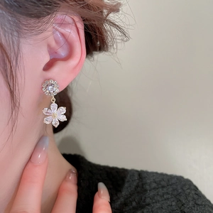 Elegant gold flower earrings with zircon crystals shown on model in side profile