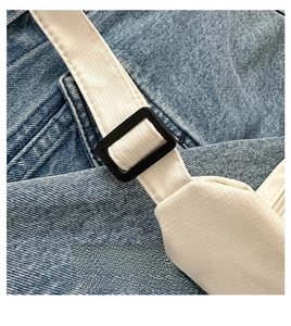 Detail of adjustable black buckle with cream webbing strap on blue denim tote bag