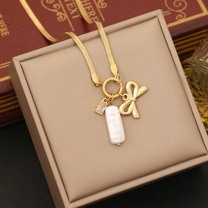 Detail of gold bow necklace with white pearl and zircon charms on jewelry box