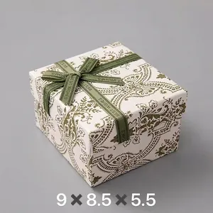 Detail of square beige gift box with green floral patterns and Best Wishes ribbon bow