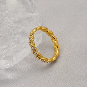 Bague torsadée dorée avec zircons brillants sur support en verre décoratif