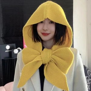 Close-up of yellow knitted hooded scarf featuring a large decorative bow on the back