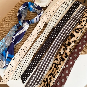 Detail of silk-feel skinny scarves featuring leopard print and geometric patterns