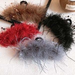 Detail of four feather hair claws in brown, red, black and grey with pearl beads