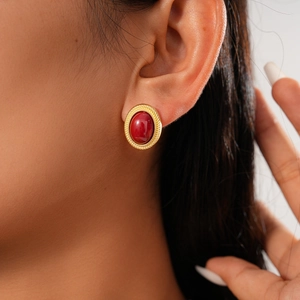Détail de boucles d'oreilles rétro avec gemme rouge ovale et bordure dorée torsadée