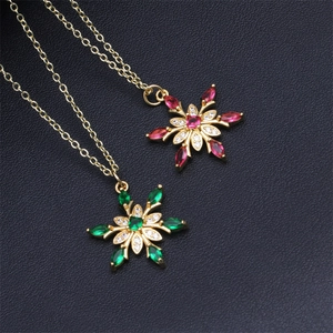 Detail of snowflake pendants featuring red and green gemstones in 18K gold-plated settings