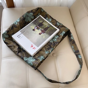 Borsa tote vintage in jacquard verde con fiori blu su superficie in pelle color crema