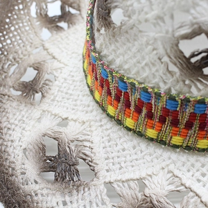 Detailed close-up of woven straw hat featuring a vibrant bohemian geometric pattern band