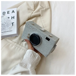 Close-up of glitter camera-shaped evening bag with silver chain and lens details