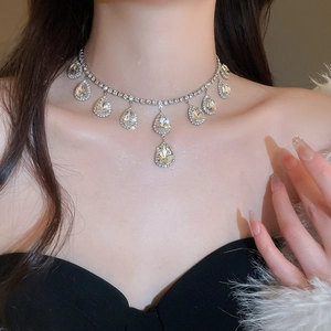 Detailed close-up of a model wearing an elegant silver teardrop rhinestone necklace