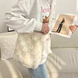Close-up of fluffy checkered shoulder bag in beige and cream faux fur texture