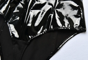 Macro detail of black patent leather bodysuit with matte fabric stitching and stitching