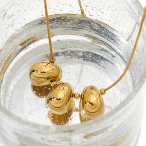 Goldene Edelstahlkette mit drei ovalen Anhängern in einer kreativen Wasserblasenszene