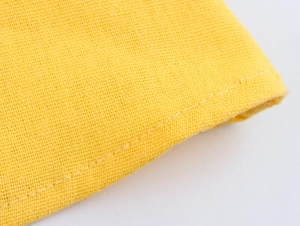 Close-up detail of yellow linen-textured fabric with high-quality hemmed stitching work