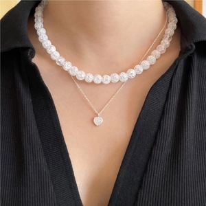 Detail view of double-layer silver necklace with heart pendant and white beaded chain