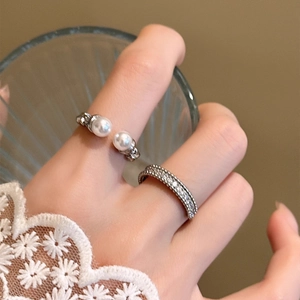 Close-up of elegant double pearl and zircon open ring set worn by a model