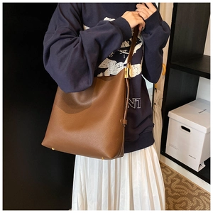 Brown litchi grain leather bucket bag featuring adjustable strap and gold metal hardware