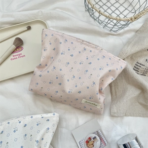 Detailed view of floral canvas makeup bags with branded label on soft fabric background