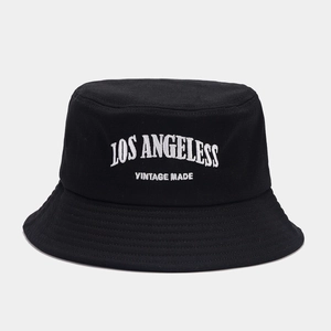 Detail of white embroidery on a black cotton bucket hat featuring vintage style text