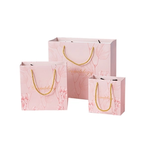 Pink paper gift bags in three sizes with gold rope handles and Cosmetology print