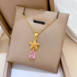 Macro shot of gold starfish necklace with pink teardrop zircon on jewelry cushion