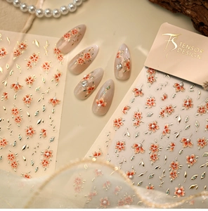 Detail of floral nail stickers with orange petals and golden embossed leaf patterns