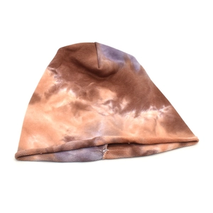 Detailed view of a brown and purple tie-dye cotton beanie with a casual rolled edge