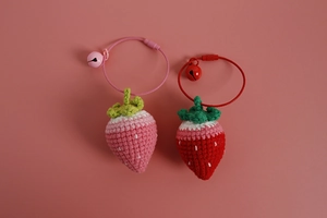 Detail of hand-knitted strawberry pendants with green leaves and matching bells