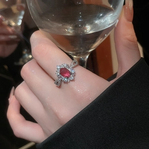 Detail of zircon oval ring with red gemstone and infinity symbol band on hand