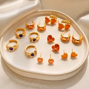 Vintage gold earrings with colorful enamel hearts and charms on a white ceramic plate