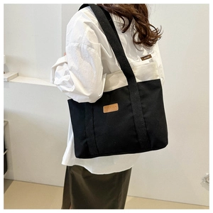 Close-up of black and white canvas tote bag with brown leather label and fashion logo