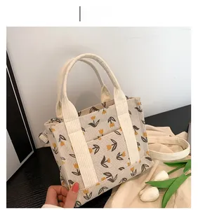 Close-up of corduroy handbag featuring yellow tulip floral print and metal strap buckle