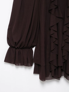 Detail eines dunkelbraunen Chiffonkleides mit Rüschen und Laternenärmeln auf weißem Hintergrund
