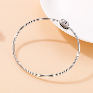 Sleek silver stainless steel open bangle with engraved Love lettering on beige background