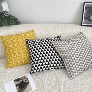 Modern geometric patterns on cotton linen throw pillow covers placed on a plush white sofa