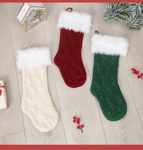 Drei gestrickte Weihnachtssocken in Creme, Rot und Grün mit weißem Kunstpelzrand