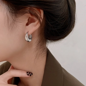 Close-up of minimalist silver water drop hoop earrings worn on a model's earlobe