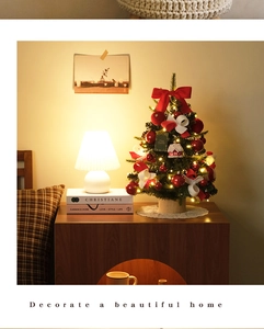 Mini tabletop Christmas tree with warm LED lights, red bows and ornaments on wooden base