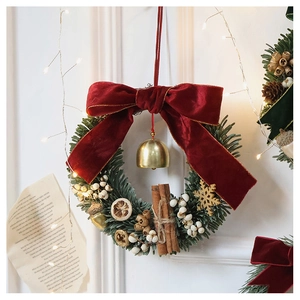 Close-up of artificial pine wreath with velvet red bow, cinnamon sticks and golden bell
