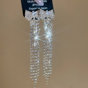 Detailed macro view of sparkling silver tassel bow earrings with high-grade rhinestones