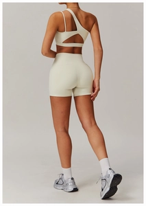 Détail de la brassière de sport asymétrique et du short de fitness blanc cassé pour femme