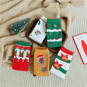 Close-up of cozy Christmas coral fleece socks with festive reindeer and tree patterns